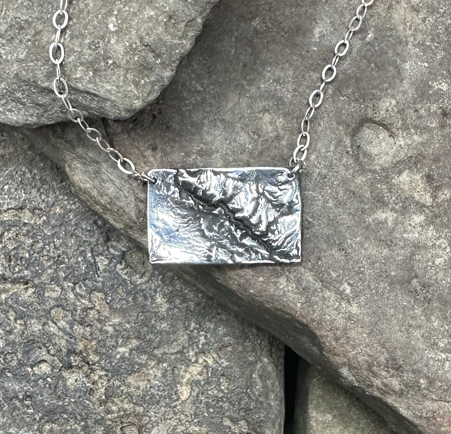 Close up of the Black Canyon of the Gunnison River necklace in silver.