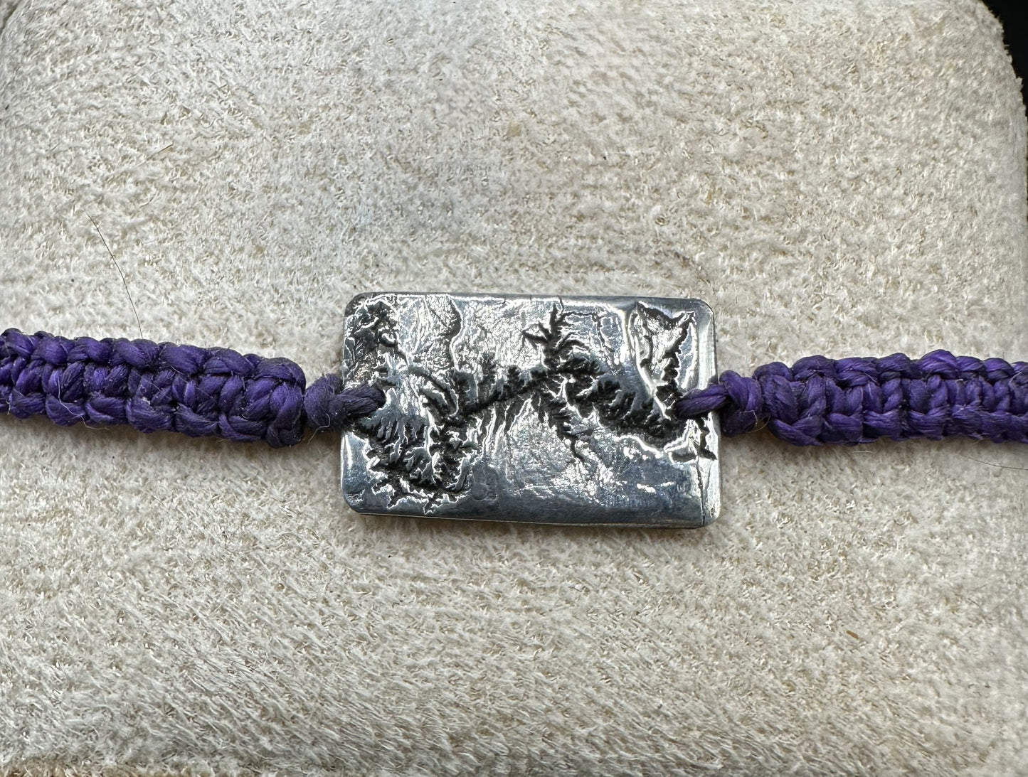 A handcrafted silver bracelet showing the topographic contours of the Grand Canyon – front view knotted purple bracelet