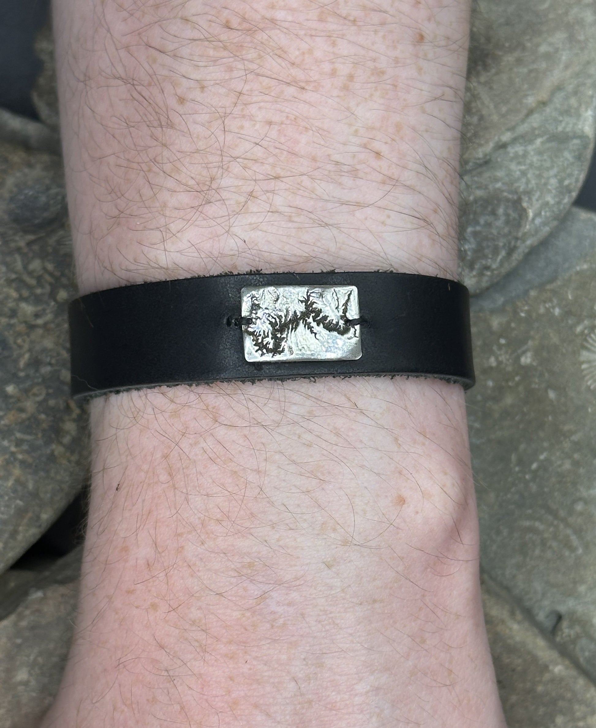 A handcrafted silver and leather bracelet showing the topographic contours of the Grand Canyon – front view