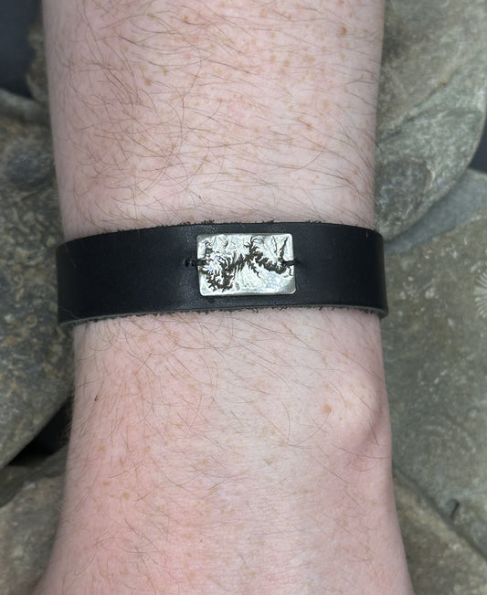 A handcrafted silver and leather bracelet showing the topographic contours of the Grand Canyon – front view