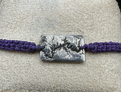 A handcrafted silver bracelet showing the topographic contours of the Grand Canyon – front view knotted purple bracelet 