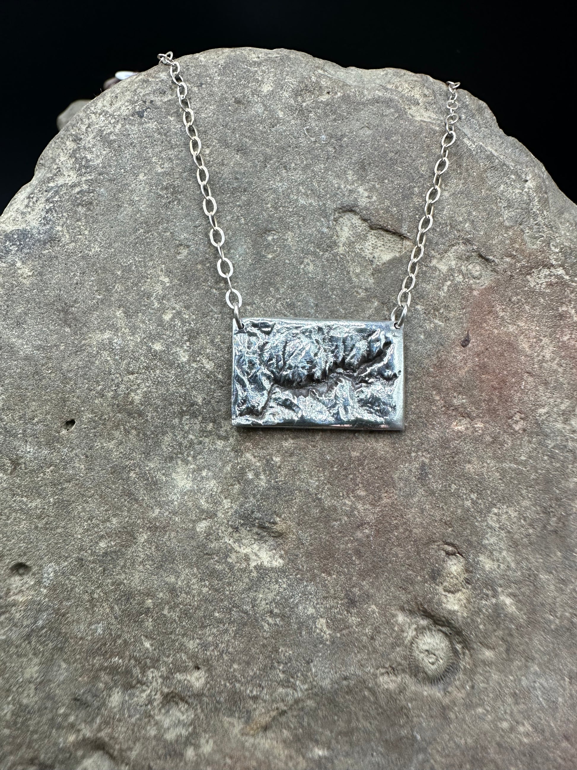 A  handcrafted silver necklace showing the topographic contours of Yosemite – front view