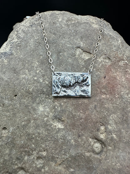 A  handcrafted silver necklace showing the topographic contours of Yosemite – front view